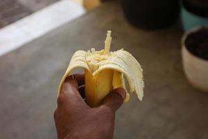 hält eine geschälte und gegessene Banane. foto
