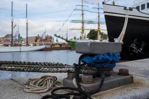 Modernes Schiff, das mit Kabeln vor dem Hintergrund von Yachten am Pier festgemacht ist. foto