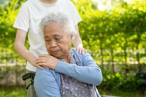 pflegekraft hilfe und pflege asiatische seniorin oder ältere alte dame patientin sitzt im rollstuhl im park, gesundes starkes medizinisches konzept. foto