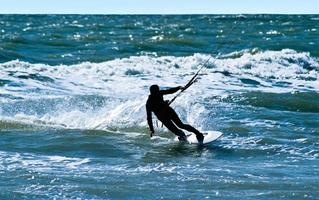 Silhouette eines Kitesurfers auf den Wellen eines Meeres foto