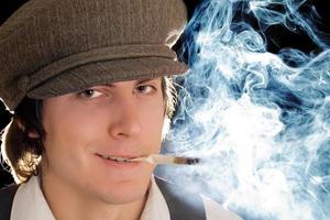 junger Mann, der eine Zigarette in Vintage-Kleidung raucht foto