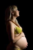 glückliche schwangere junge Frau in gelben Dessous. isoliert foto