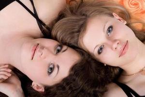 Porträt der beiden jungen Schönheitsfrauen, die auf einem Kissen liegen 2 foto