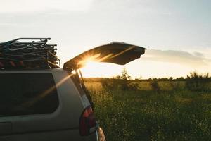 Nahaufnahme eines Fahrzeugs mit Foul-Radantrieb in der Natur mit offenem Kofferraum. Öffnen Sie den Kofferraum eines Offroad-Autos mit Gepäck im Inneren auf einem Berg bei Sonnenuntergang. Feiertage und Wochenenden. Aktiver Tourismus. foto