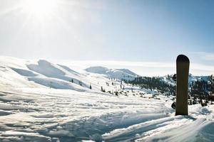schwarze Basis des Snowboards im Schnee mit weißen Bergen im Hintergrund. konzept der neuen skisaison. foto