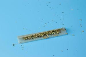 Unkraut in Papier für Joint auf blauem Hintergrund. Cannabisrauchen, Marihuana-Shop, Kopierraum foto