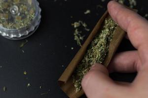 hand hält cannabis in stumpfem rollenpapier. konzept für medizinische und freizeitnutzung von marihuana. Selbstpflege mit Kräuterkraut foto