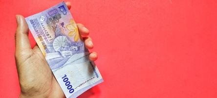 Mann mit indonesischer 10.000-Rupiah-Banknote, neueste Ausgabe foto
