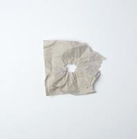 graues, zerknittertes Blatt Papier mit einem Loch foto