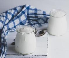 Gläser mit hausgemachtem Joghurt auf einem weißen Holzbrett foto