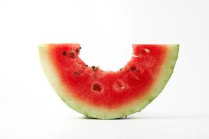 ein Stück reife rote runde Wassermelone mit Samen abgebissen foto