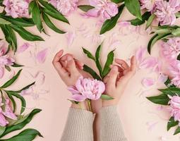 Zwei Hände eines jungen Mädchens mit glatter Haut und einem Strauß rosa Pfingstrosen foto