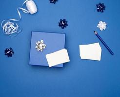 quadratische geschenkboxen aus pappkarton, schleifen, bänder zum verpacken auf dunkelblauem hintergrund foto