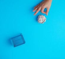 Hand schob einen Ball aus zerknülltem grauem Papier in einen Papierkorb aus Metall foto