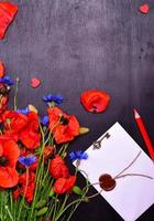 rote Mohnblumen und blaue Kornblumen mit einem versiegelten Umschlag foto