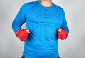 erwachsener athlet in blauer kleidung, hände in einen roten elastischen verband gewickelt foto