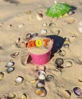 Eiseneimer mit bunten Holzbuchstaben steht auf dem Sand foto