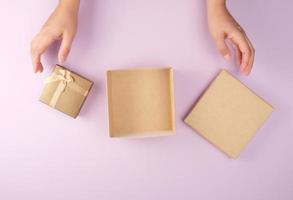 Mädchen öffnet eine braune quadratische Schachtel auf violettem Hintergrund foto