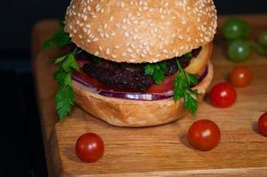 Leckerer Burger mit Fleischkoteletts, serviert auf einem Holzbrett foto