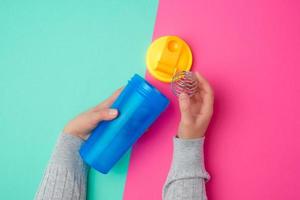 blaue Shaker-Flasche aus Kunststoff mit gelbem Verschluss und einer Eisenkugel für Sportler foto