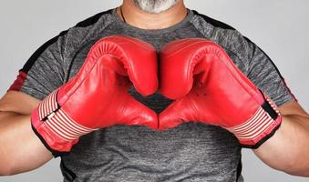 Sportler in roten Boxhandschuhen aus Leder zeigt Hände mit einem Herzsymbol foto