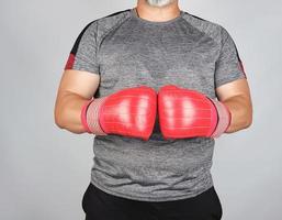 muskulöser erwachsener athlet in grauer uniform und roten lederboxhandschuhen foto