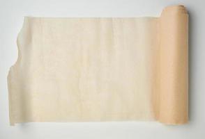 hellbraune Rolle mit Pergamentpapier auf weißem Hintergrund gesponnen foto