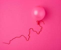 aufgeblasener rosa luftballon auf dem rosa hintergrund foto