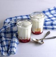 zwei Glasgläser mit hausgemachtem Joghurt und Himbeersirup foto