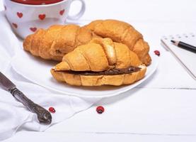 gebackene Croissants mit Schokolade auf einem weißen Teller foto