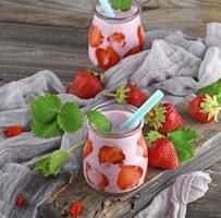 erdbeerjoghurt in einem glas mit plastikstrohhalm foto
