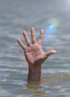 Die Hand des rechten Mannes ragt mitten im Ozean aus dem Wasser foto