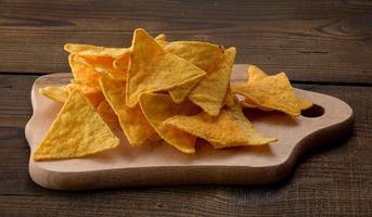 Haufen von Mais-Tortilla-Chips oder Nachos auf braunem Holzhintergrund foto