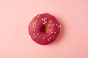 roter runder donut mit weißen streuseln auf einem rosa hintergrund foto