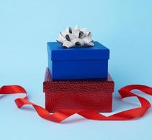 Stapel verpackter Geschenke mit geknoteten Schleifen auf blauem Hintergrund foto