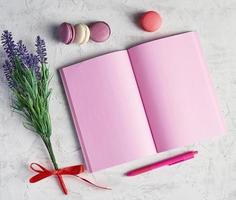 offenes notizbuch mit leeren rosa seiten, roter stift foto