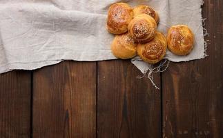 Gebackene runde Brötchen auf einem Holztisch, Draufsicht foto