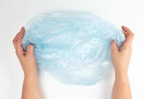 blauer Müllsack aus Plastik in weiblichen Händen auf weißem Hintergrund foto