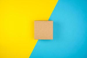 quadratische braune Geschenkbox auf gelb-blauem Hintergrund foto