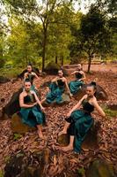eine gruppe indonesischer tänzer, die wunderschön auf dem felsen sitzen, mit braunen blättern im hintergrund im wald foto