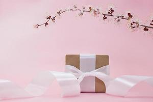 zweig der kirsche, aprikose, sakura mit geschenkbox mit band auf rosa hintergrund. feiertage, internationaler frauentag, muttertag, geburtstag, 8. märz. kopierraum foto