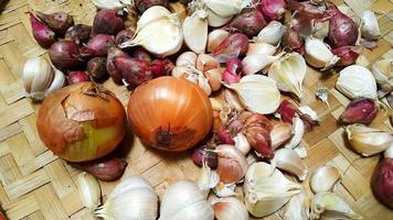 Nahaufnahme von Schalotten, Knoblauch und Zwiebeln auf einem Tablett aus Rattan foto