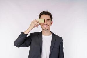 Porträt des jungen lächelnden hübschen Geschäftsmannes, der die Kreditkarte lokalisiert über weißem Hintergrund zeigt