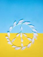 Peace-Zeichen von weißen Blütenblättern auf dem blauen und gelben Hintergrund. Farben der ukrainischen Flagge foto