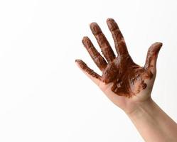 weibliche hand verschmutzt in geschmolzener schwarzer schokolade auf weißem hintergrund foto
