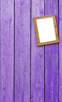 lila Holzwand, an der ein leerer Fotorahmen aus Holz hängt foto