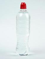 transparente Plastikflasche mit frischem Wasser auf weißem Hintergrund foto