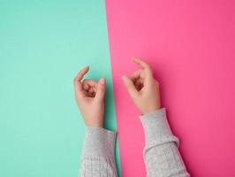 weibliche hände auf einem grün-rosa hintergrund, finger in der geste, das thema zu halten foto