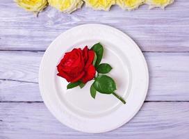 leere weiße Platte mit einer roten Rose foto
