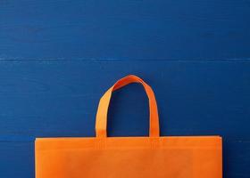 wiederverwendbarer orangefarbener Viskosebeutel auf blauem Holzhintergrund foto